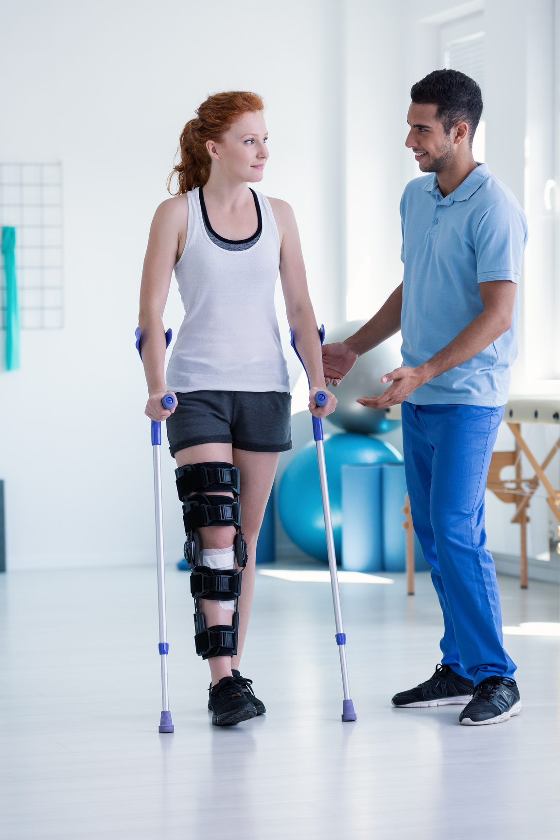 Professional physiotherapist taking care of sportswoman during rehabilitation